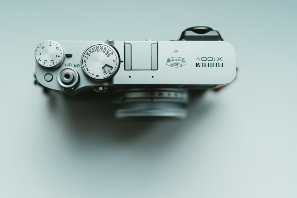 Vista superior de una cámara Fujifilm X100V plateada con sus diales de velocidad y compensación de exposición