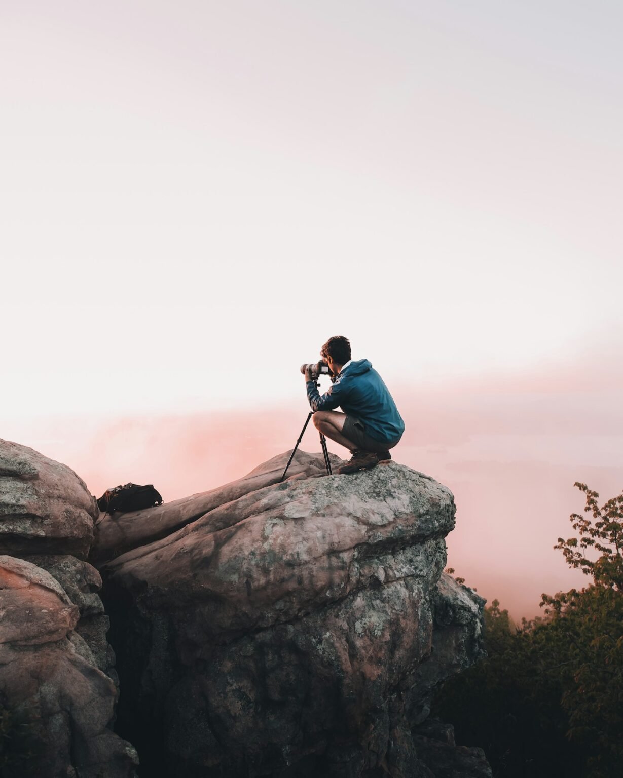 Fotógrafo agachado sobre una roca encuadrando un paisaje al amanecer