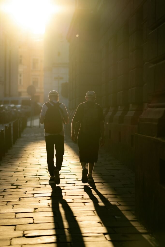 Dos personas caminando de espaldas a contraluz por una calle estrecha