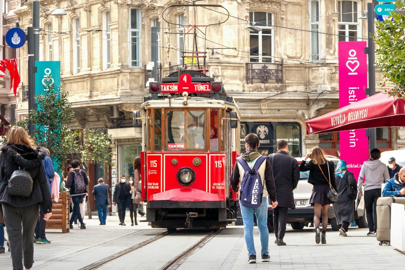 Tranvía rojo avanzando entre peatones por una calle comercial de Estambul