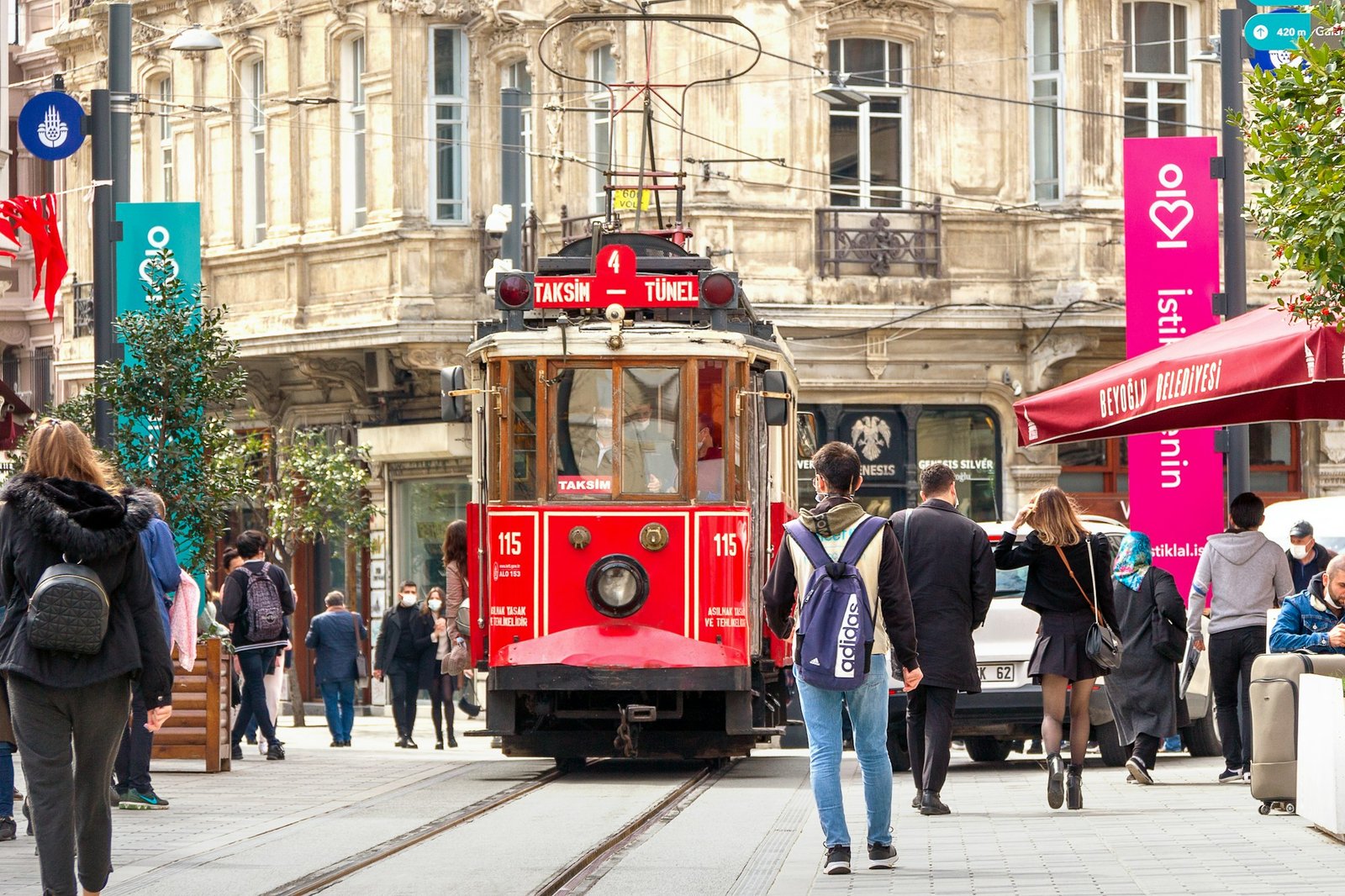 Tranvía rojo avanzando entre peatones por una calle comercial de Estambul
