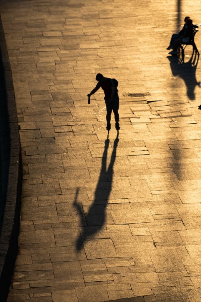 Silueta de un peatón y su sombra alargada sobre adoquines iluminados por el sol bajo