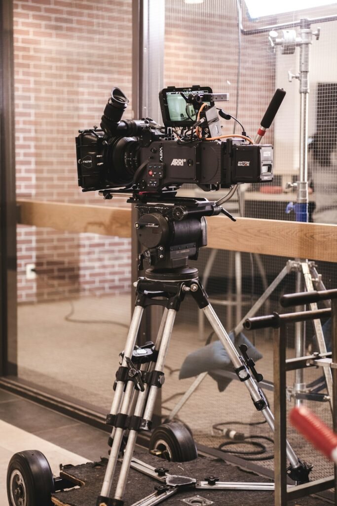 Cámara de cine con monitor montada en un trípode, preparada para grabar junto a una ventana